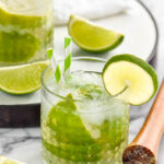 two glasses of Caipiroska recipe with ice garnished with straws and limes
