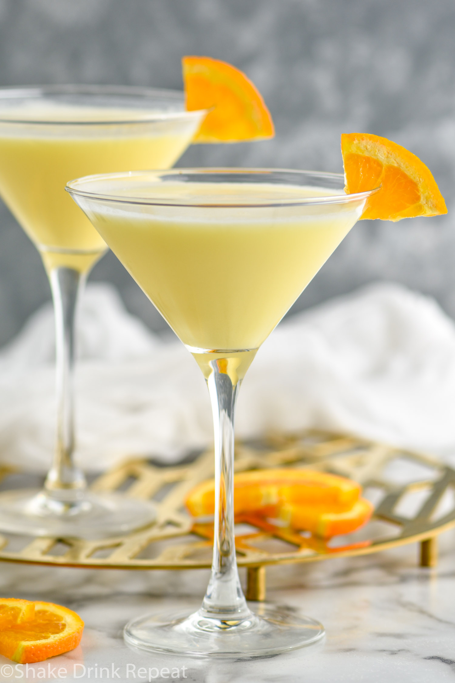 two martini glasses of Golden Dream recipe garnished with an orange slice