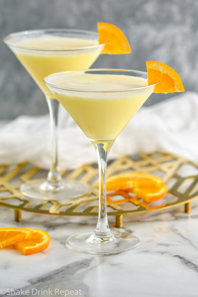 two martini glasses of Golden Dream recipe garnished with an orange slice