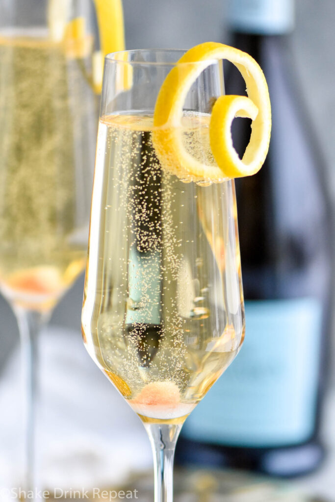 two champagne flutes of Champagne Cocktail garnished with a lemon twist