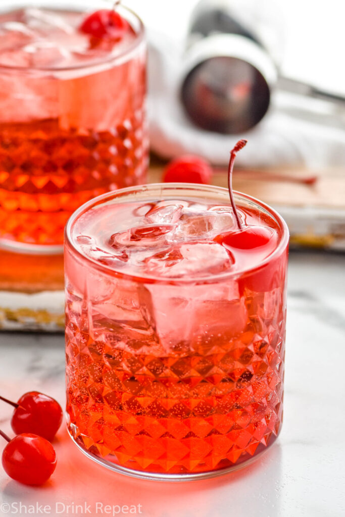 Two glasses of Dirty Shirley drinks with ice and maraschino cherries