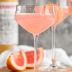 Two glasses of Hemingway Daiquiri recipe garnished with grapefruit twist with bottle of Luxardo in the background