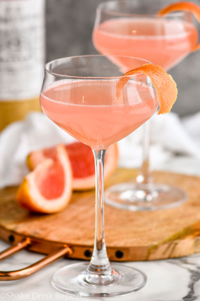 Two glasses of Hemingway Daiquiri recipe garnished with grapefruit twist with bottle of Luxardo in the background