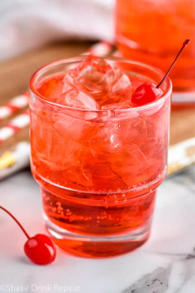 close up of two glasses of Shirley Temple drink with ice and garnished with maraschino cherries