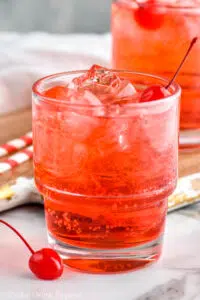 close up of two glasses of Shirley Temple drink with ice and garnished with maraschino cherries