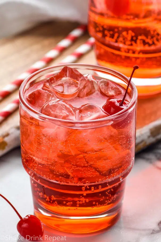 close up of two glasses of Shirley Temple drink with ice and garnished with maraschino cherries