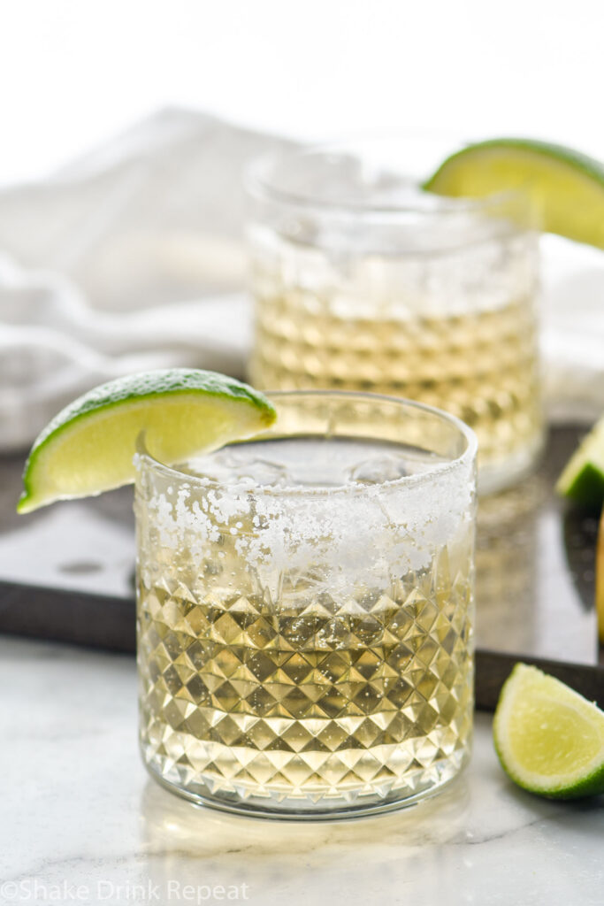 Two glasses of Tequila and Ginger Ale with ice, salted rim and wedge of lime for garnish