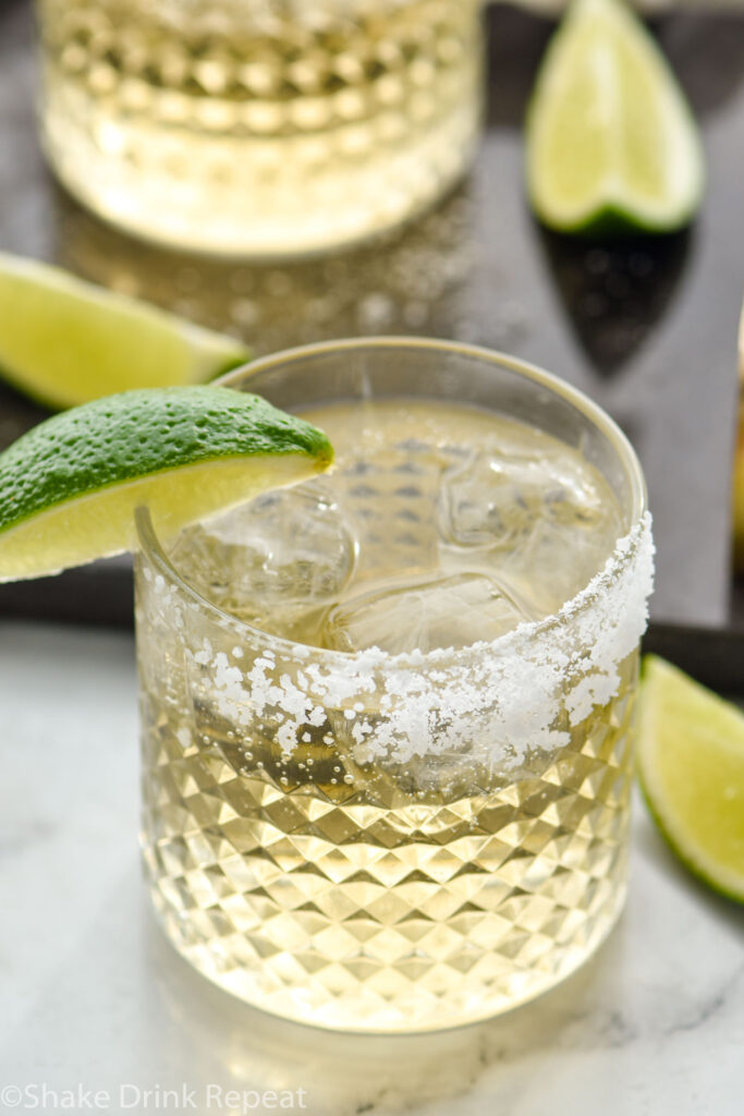 Two glasses of Tequila and Ginger Ale with ice, salted rim and wedge of lime for garnish