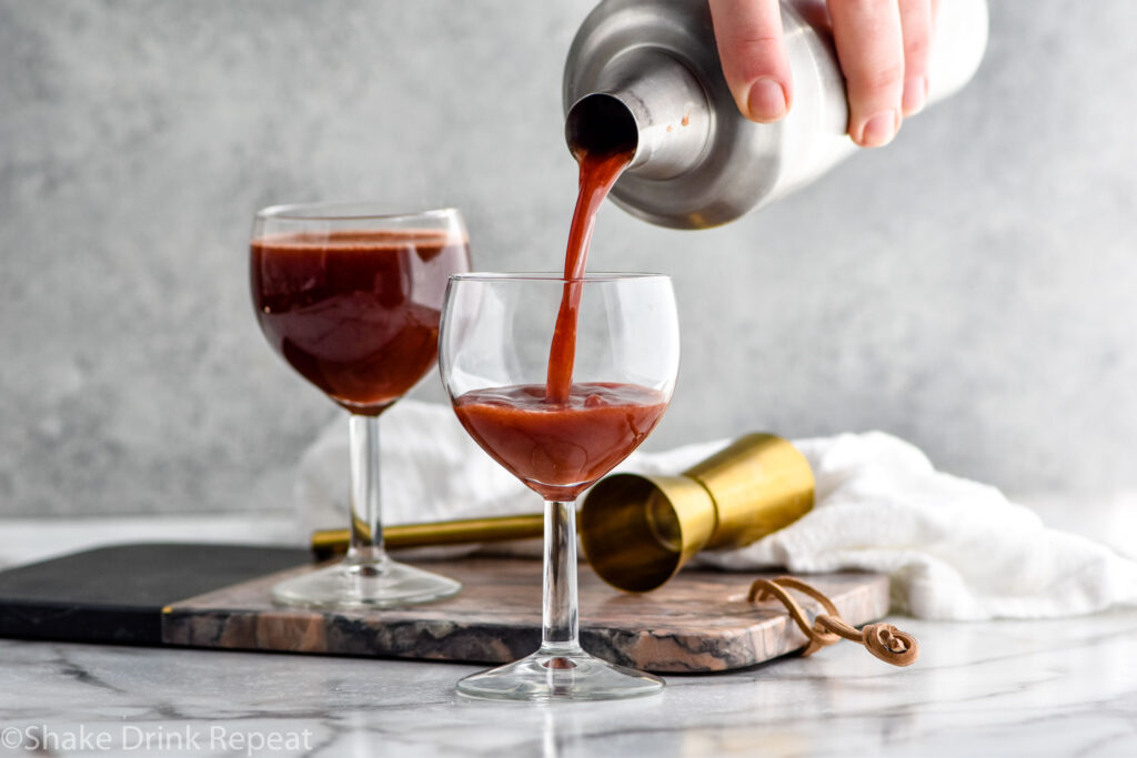 man's hand pouring cocktail shaker of Trinidad Sour ingredients into a glass