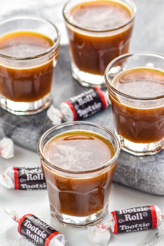 Shot glasses of Tootsie Roll Shot recipe surrounded by Tootsie Roll candies