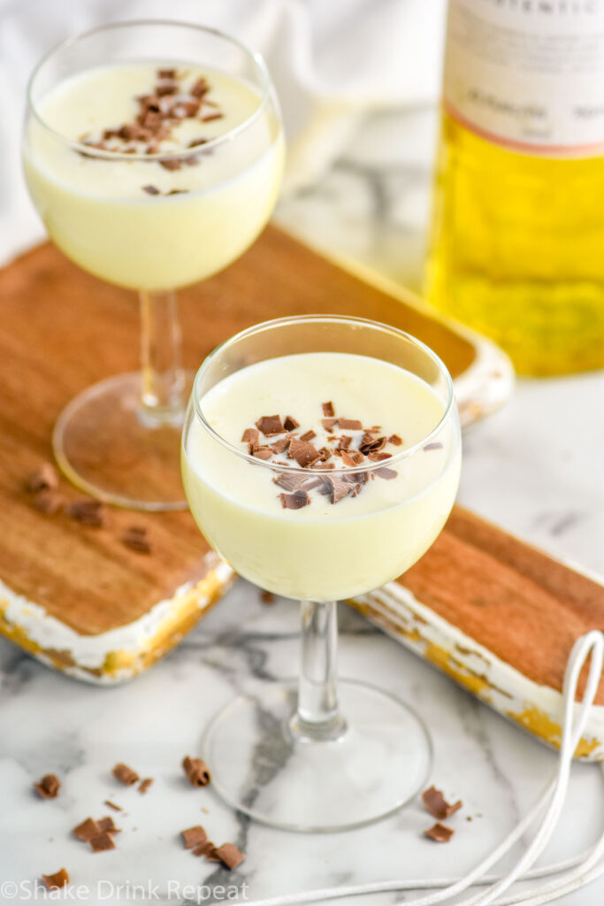 Two glasses of Golden Cadillac recipe garnished with chocolate shavings with bottle of Galliano in the background