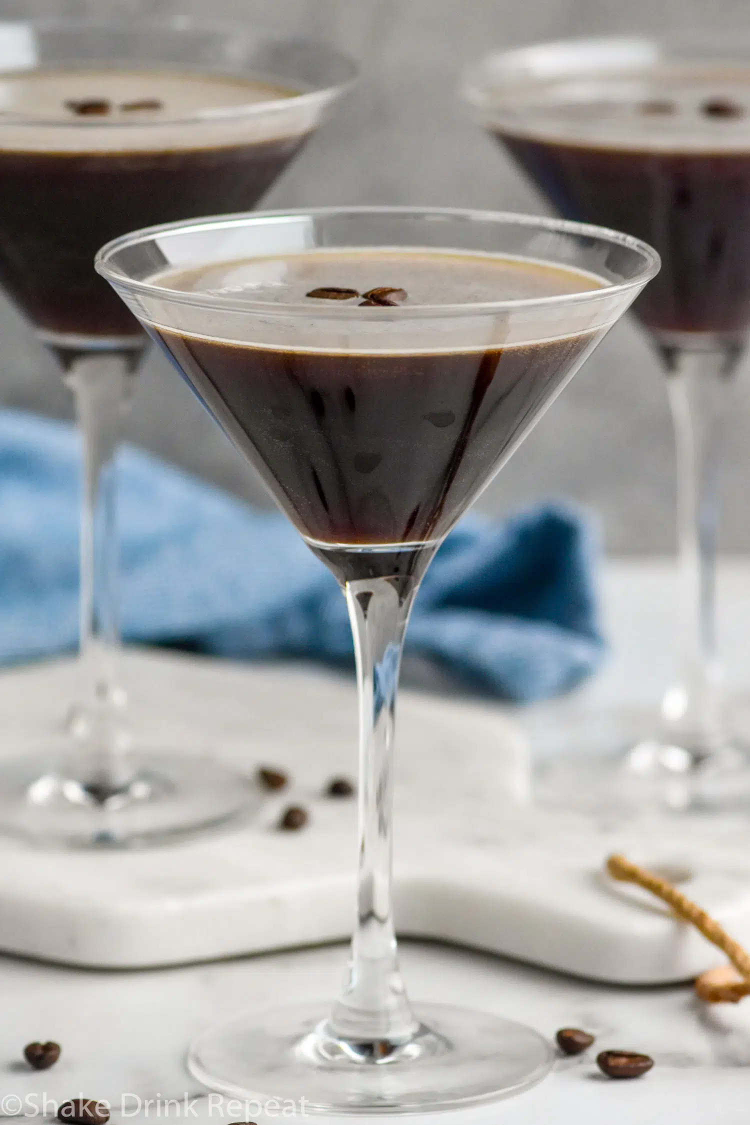 three martini glasses of Espresso Martini garnished with espresso beans