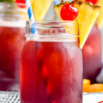 three glasses of Rum Runner with ice, garnished with fresh pineapple wedge, a cherry, and a straw
