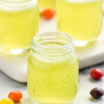 four shot glasses of Skittles Shot recipe surrounded by Skittles candy