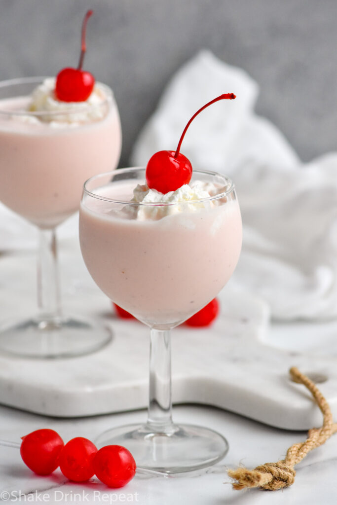 two glasses of Pink Squirrel with Ice Cream garnished with whipped cream and a cherry