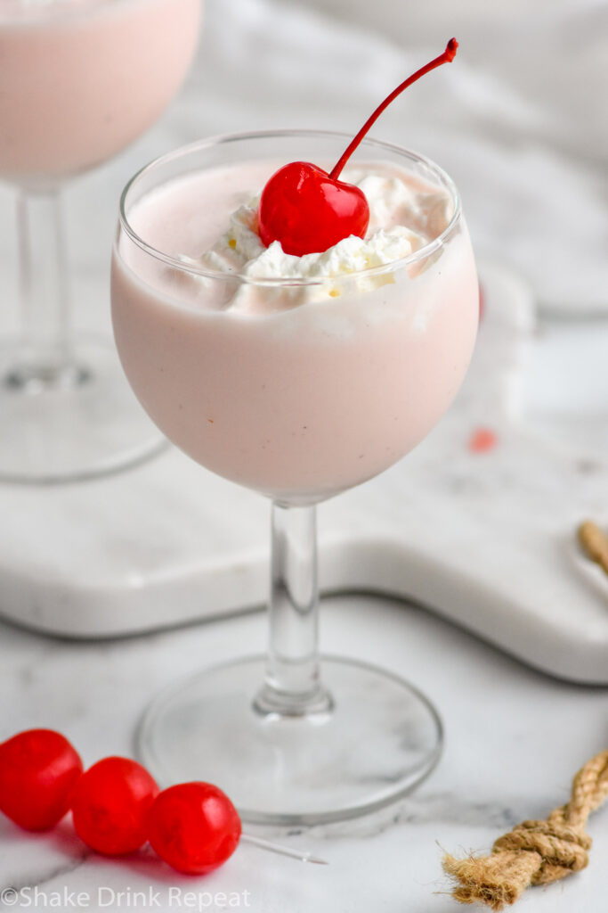 glass of Pink Squirrel with Ice Cream garnished with whipped cream and a cherry