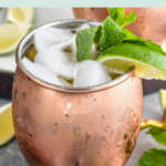 Pinterest graphic of moscow mule with gin. Text says gin, moscow mule with gin shakedrinkrepeat.com, image shows copper mug of moscow mule with gin with ice, mint leaves and a lime with bottle opener laying in front