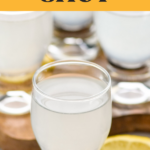 Pinterest graphic of White Tea Shot. Text says "white tea shot vodka shakedrinkrepeat.com" image shows glass of white tea shot with lemon slices laying beside.