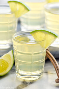 shot glass of green tea shot garnished with a lime wedge