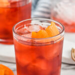 Photo of mezcal negroni cocktail in a tumbler with ice and garnished with an orange peel.