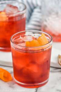 Photo of mezcal negroni cocktail in a tumbler with ice and garnished with an orange peel.