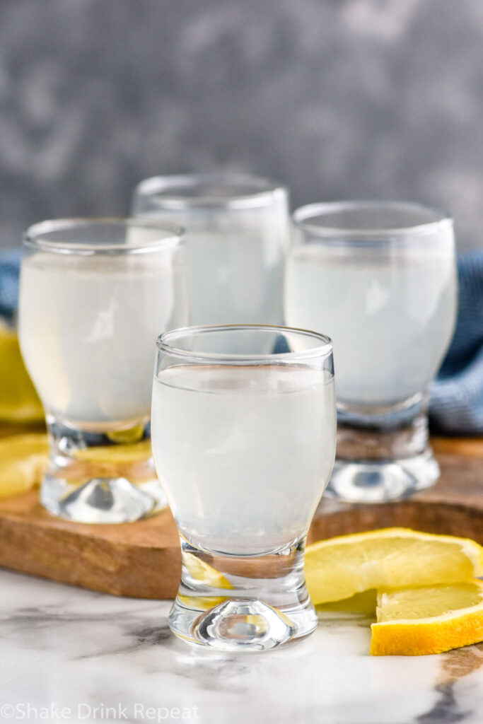 Four glasses of white tea shot recipe surrounded by lemon slices