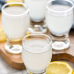 Four glasses of white tea shot recipe surrounded by lemon slices