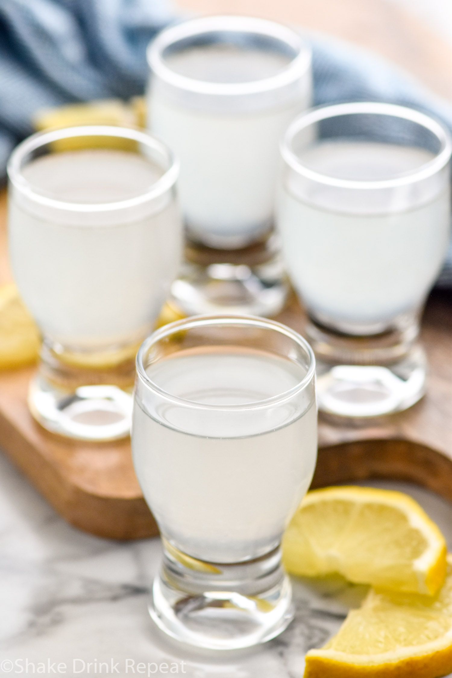 Four glasses of white tea shot recipe surrounded by lemon slices