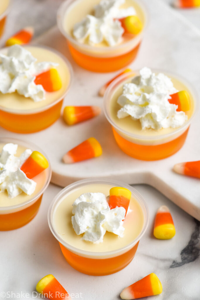 shot glasses of candy corn jello shots topped with whipped cream and candy corn candy