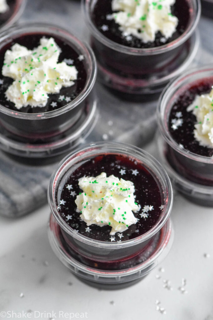 Overhead photo of Drunk Witch Jell-O Shots garnished with whipped cream and sprinkles.