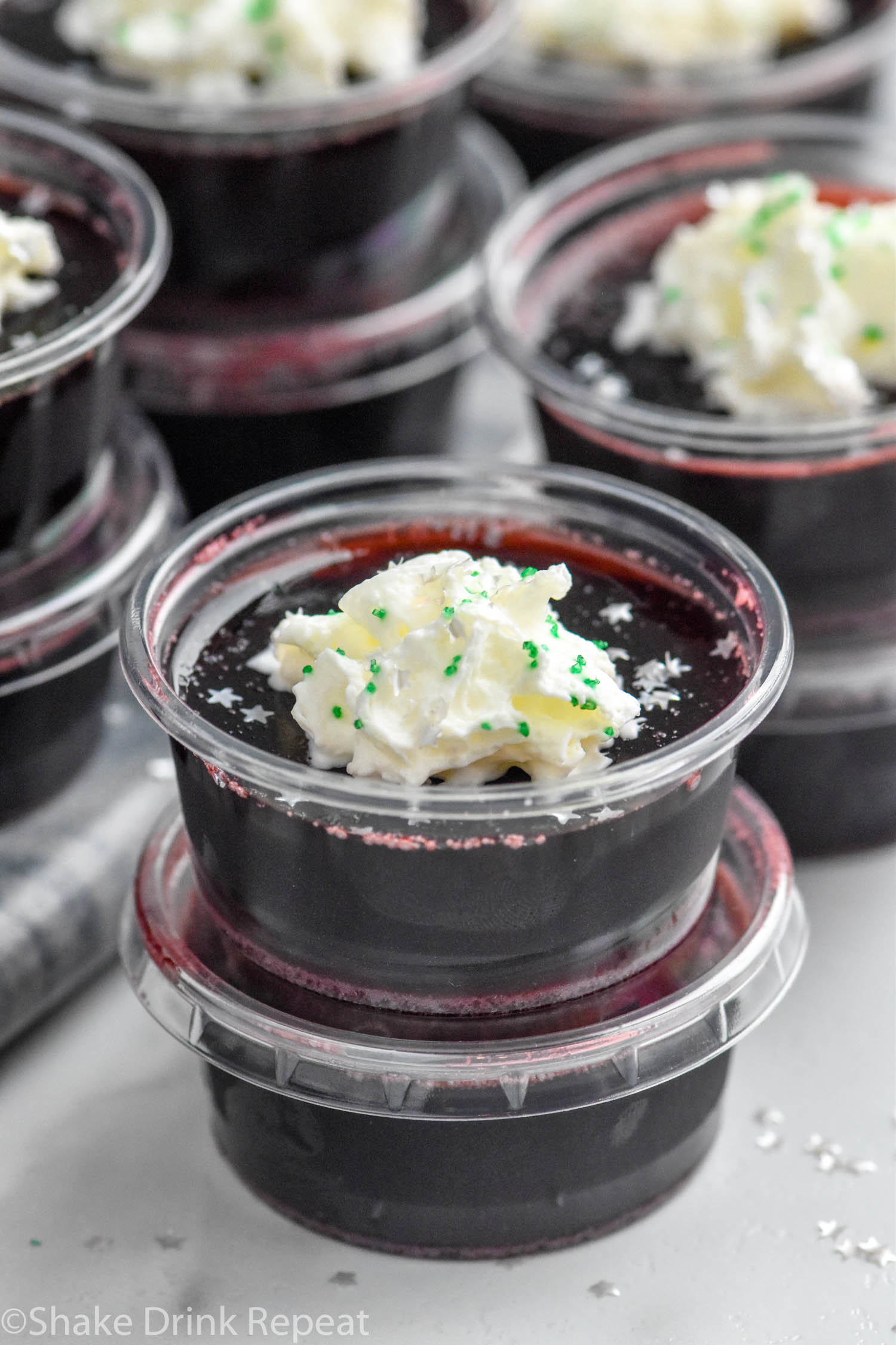 Overhead photo of Drunk Witch Jell-O Shots garnished with whipped cream and sprinkles.