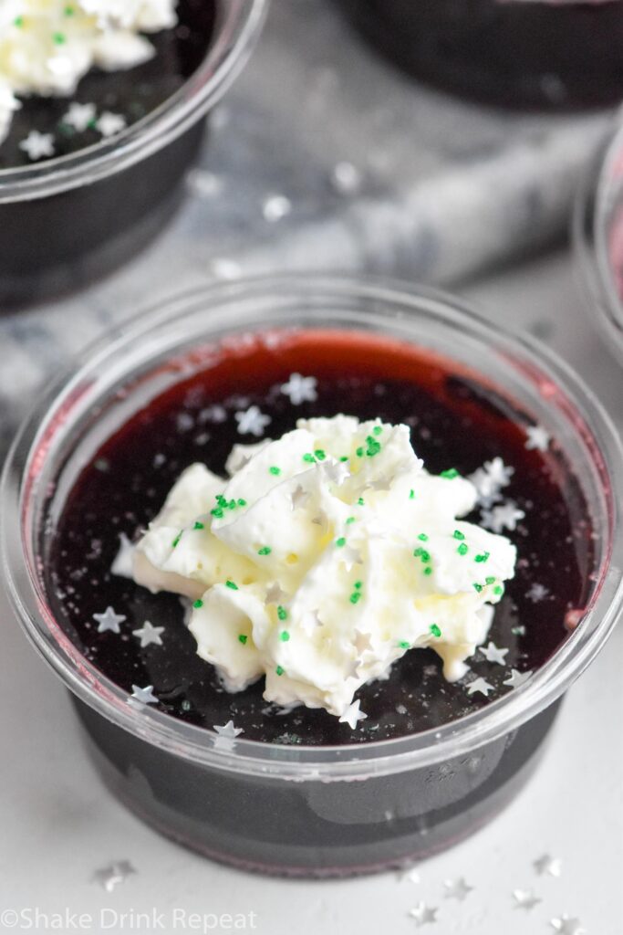 Overhead photo of Drunk Witch Jell-O Shots garnished with whipped cream and sprinkles.