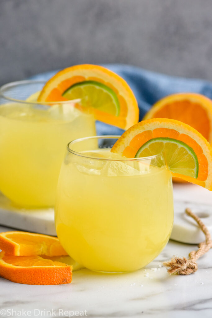 Overhead photo of Texas Margarita recipe served in two glasses, each garnished with an orange slice and a lime wedge.