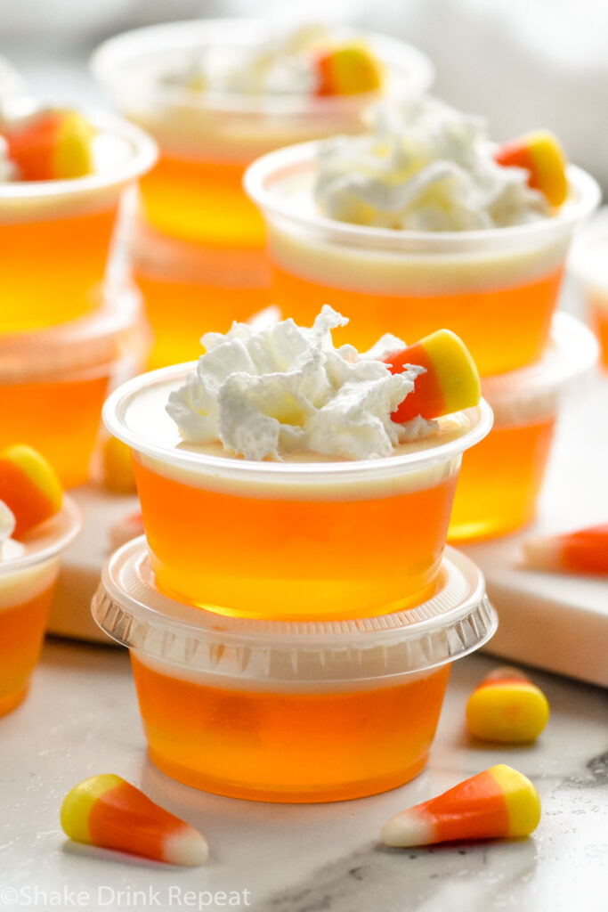 shot glasses of candy corn jello shots topped with whipped cream and candy corn candy