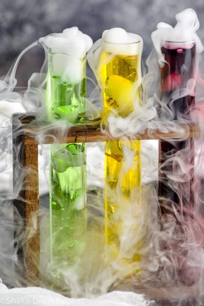 three test tubes of mad scientist shots in a wooden holder with dry ice causing smokey appearance