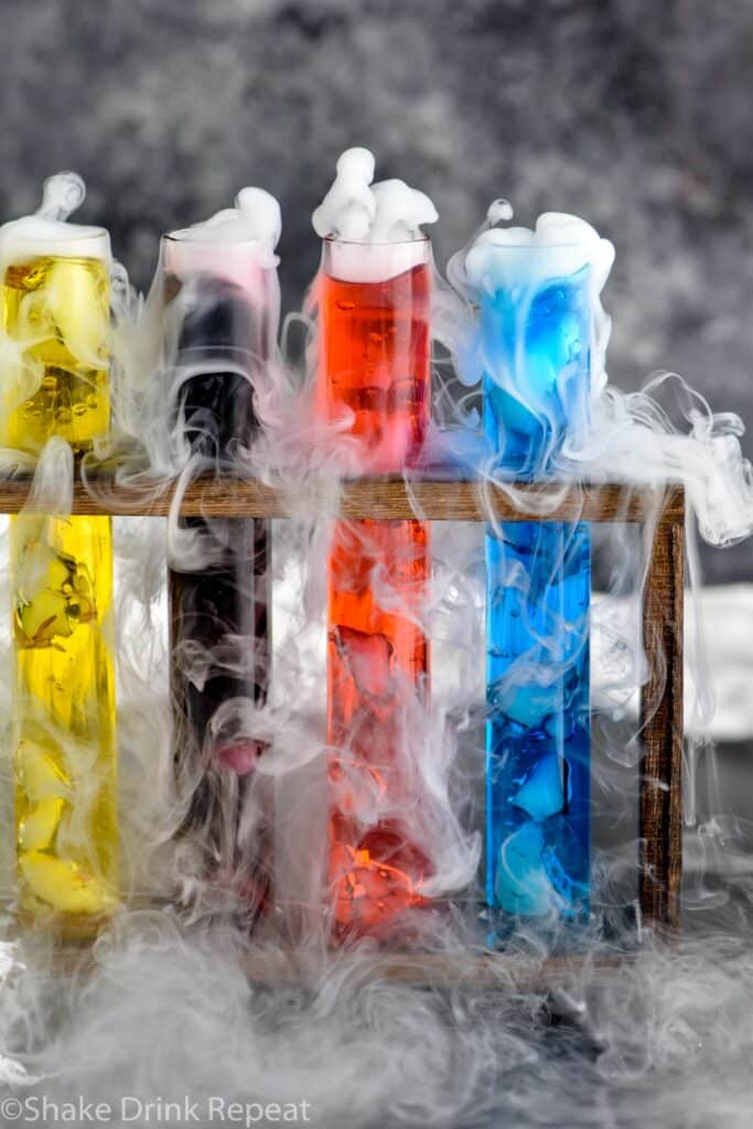 four test tubes of mad scientist shots in a wooden holder with dry ice causing smokey appearance
