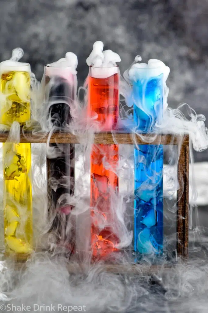 four test tubes of mad scientist shots in a wooden holder with dry ice causing smokey appearance