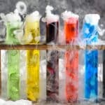 three test tubes of mad scientist shots in a wooden holder with dry ice causing smokey appearance