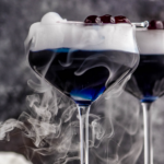 Pinterest graphic of Witches Brew cocktail. Text says "The best witches brew Only uses 3 ingredients! shakedrinkrepeat.com" Image shows two glasses of Witches Brew drink garnished with dry ice and cherries