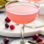two glasses of cranberry daiquiri with cranberries laying beside