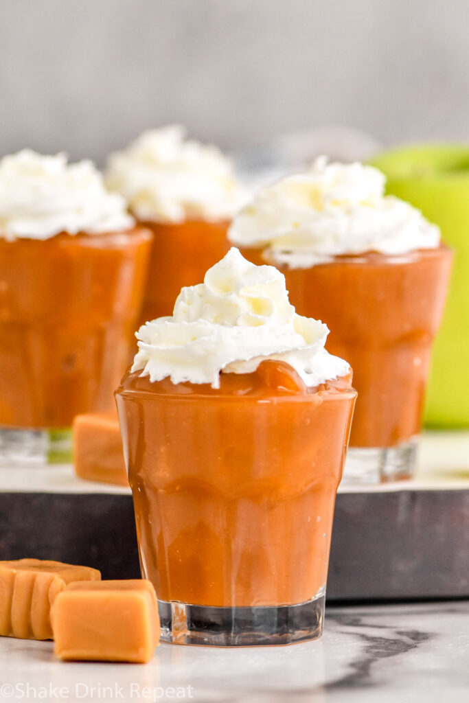 Photo of Caramel Apple Pudding Shots garnished with whipped cream.