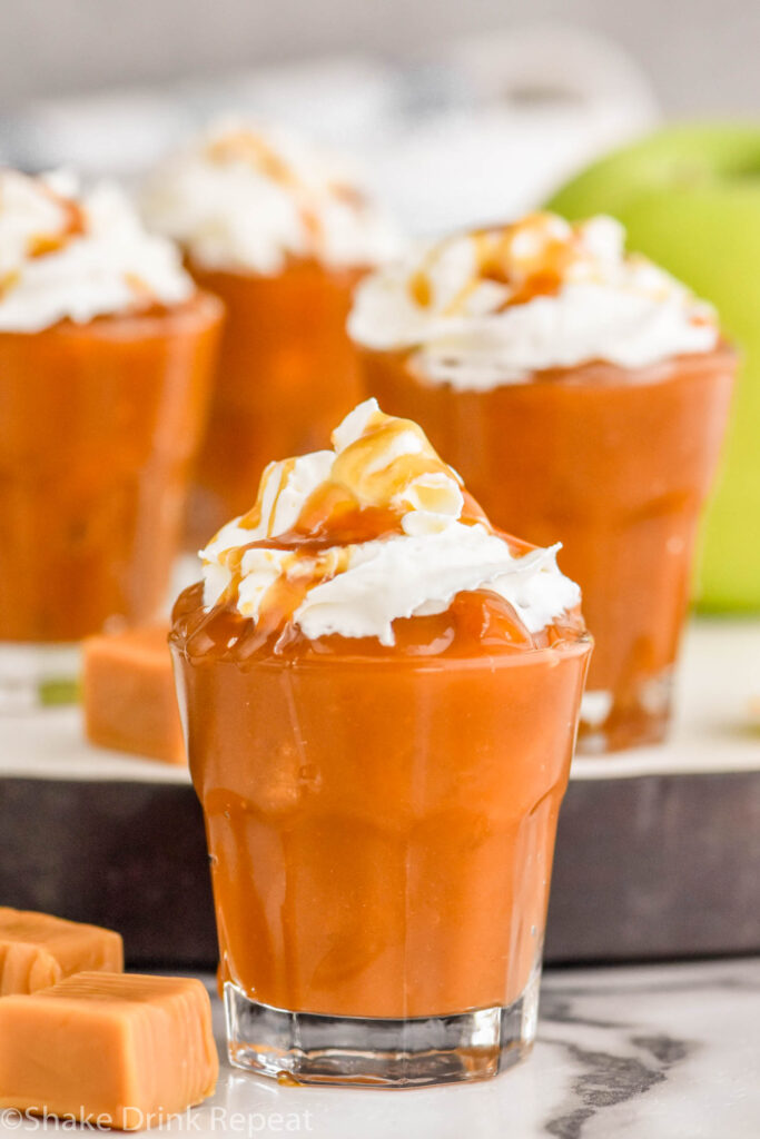 Photo of Caramel Apple Pudding Shots garnished with whipped cream and caramel.