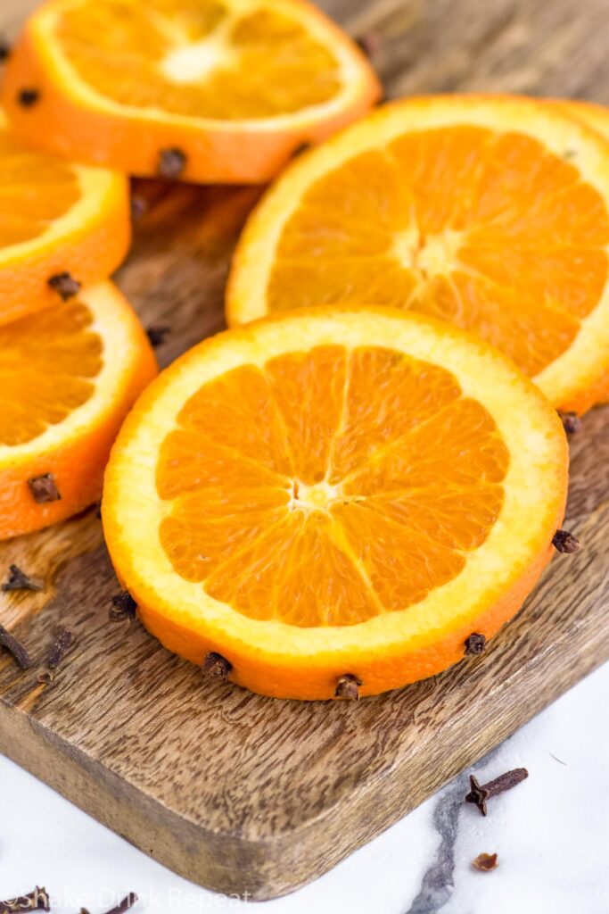 sliced oranges with cloves in rind to make spiced apple cider in crock pot