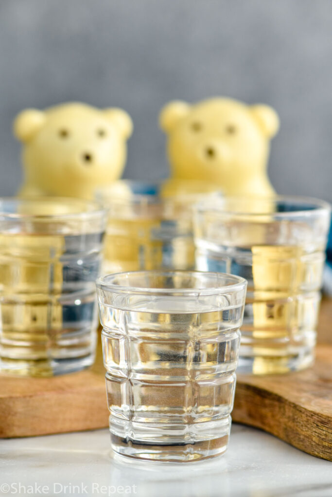 Four shot glasses of polar bear shots with polar bear hot cocoa bombs for garnish sit in background