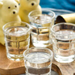 Four shot glasses of polar bear shots with polar bear hot cocoa bombs for garnish sit in background