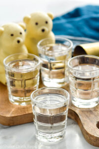 Four shot glasses of polar bear shots with polar bear hot cocoa bombs for garnish sit in background