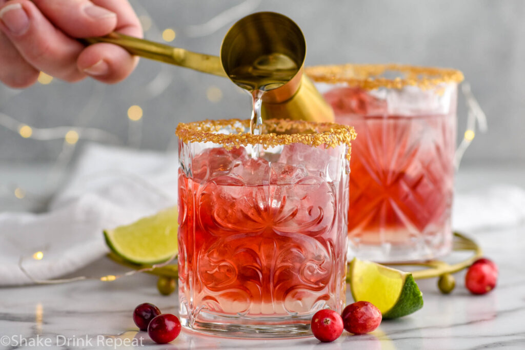 horizontal photo of triple sec being poured into cranberry margarita