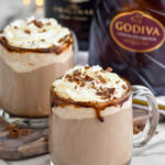 Overhead photo of Dirty Snowman Drink with two glasses of the drink and baileys and Godiva bottles in the background.