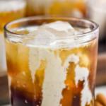 Pinterest graphic of Eggnog White Russian with a completed drink in a glass Tumblr with a cinnamon stick next to it.