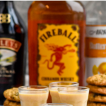 Pinterest graphic of Oatmeal Cookie Shot with three shots that have Baileys, Fireball, and Butterscotch Schnapps bottles behind it. Says, 'the best oatmeal cookie shot, shakedrinkrepeat.com'